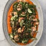 Crispy lentil salad filled with shrimp, cucumbers, and herbs on a decorative plate