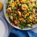 Shrimp and lentil salad with vegetables and carrot dressing on a blue platter.